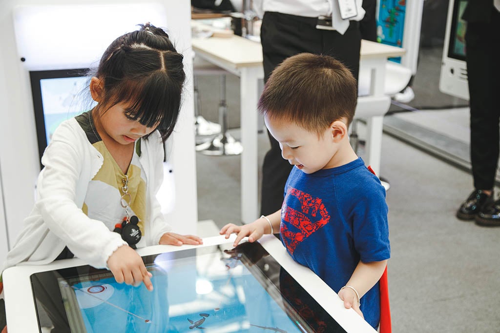 Двое детей заняты игрой с интерактивными игровыми системами IKC